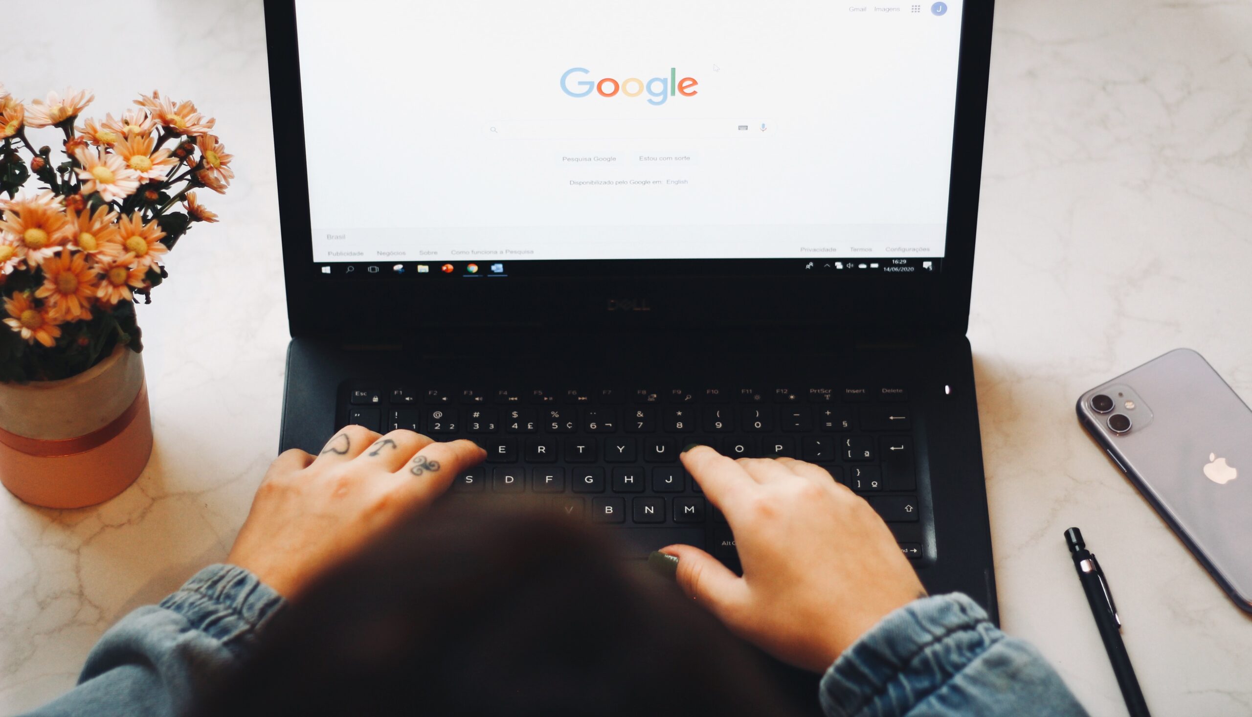 A woman typing on a laptop with the google logo on it.